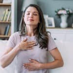 Woman doing calming breathing exercises at home.